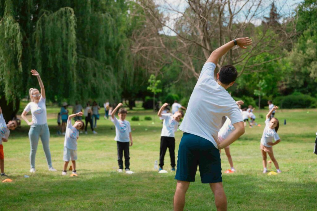 A group of children and adults enjoy stretching exercises in a park.